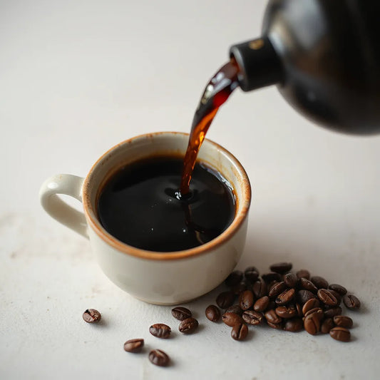 Dark roast coffee in a ceramic cup with roasted beans on a dark background