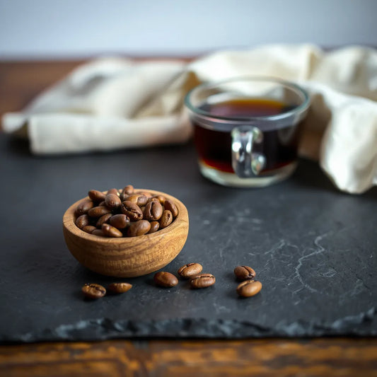 Whole guatemalan coffee beans beside a cup of freshly brewed coffee on a slate surface